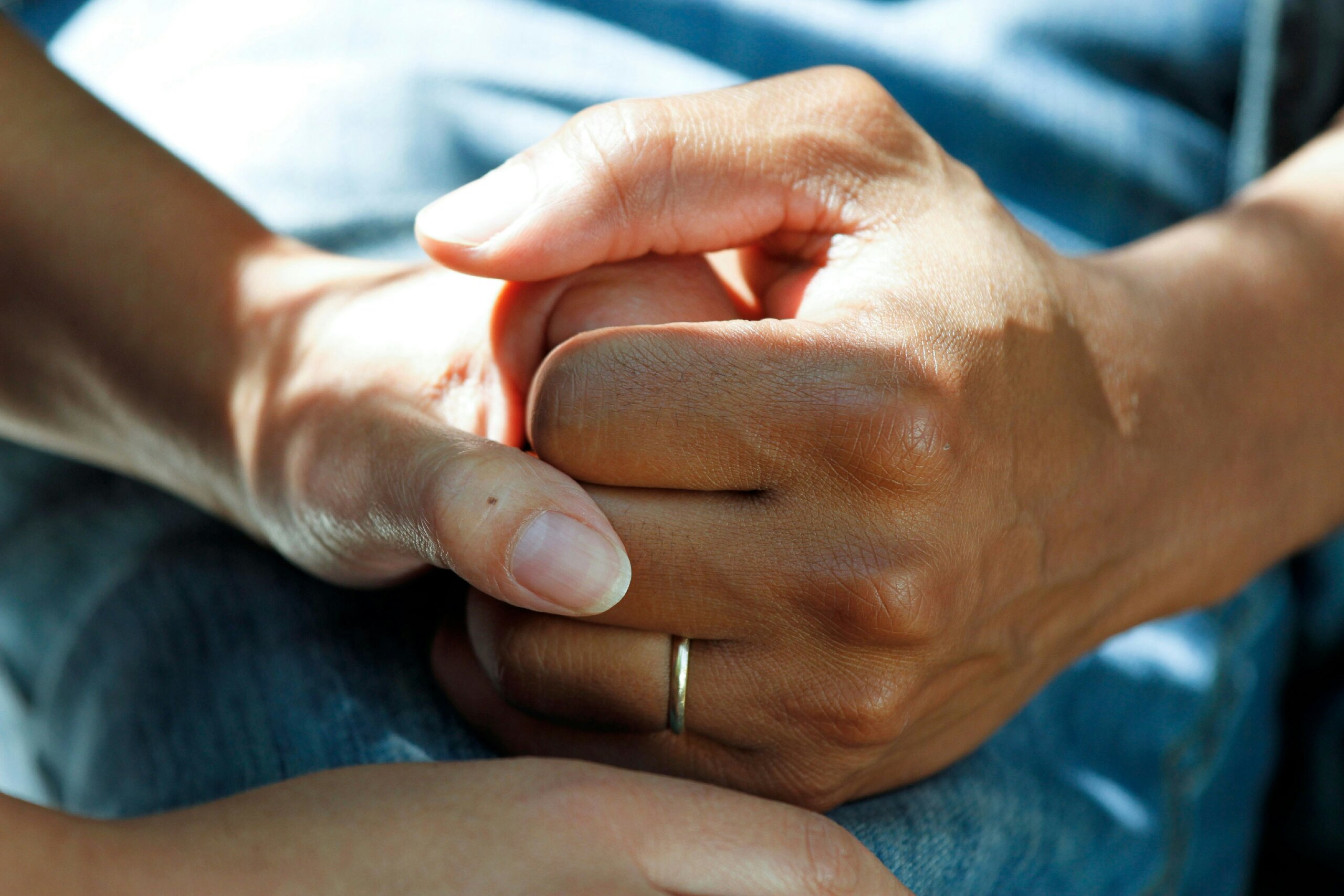 Close-up of two hands gently holding each other in comfort and support.