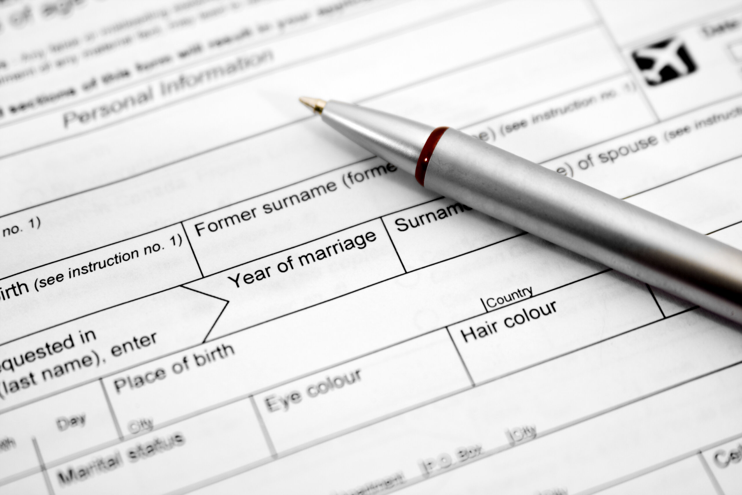 A pen sits on top of a passport application form.