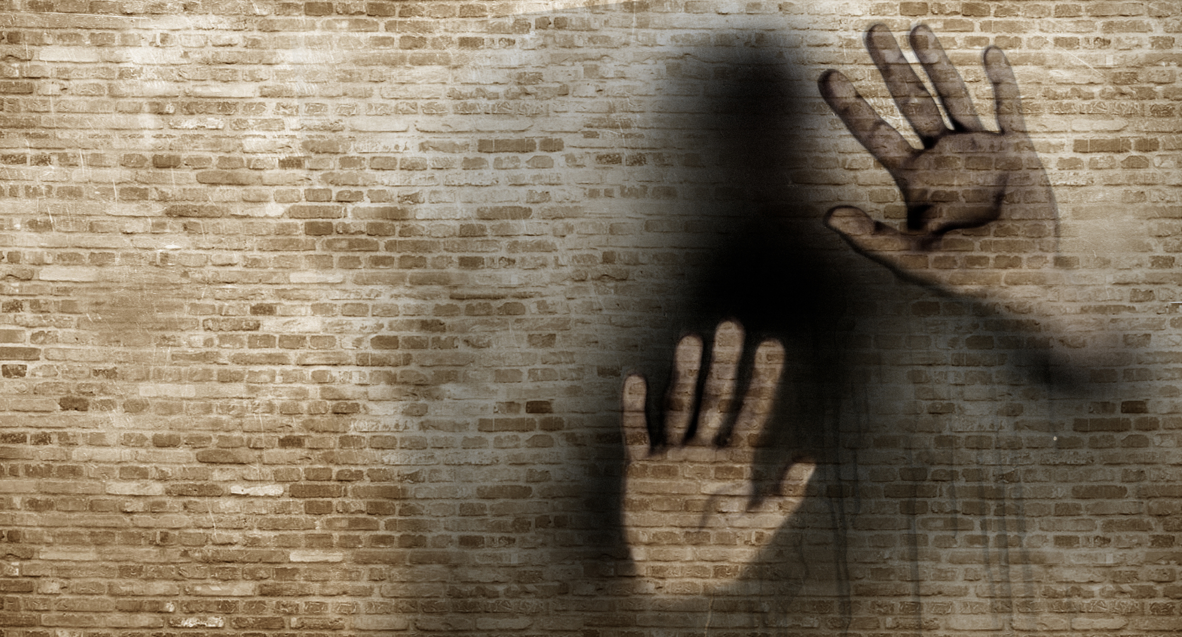 Print of human hands on a brickwall trying to come through the border