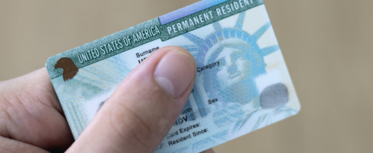 Man holding US permanent resident (green) with his hand. Immigration concept