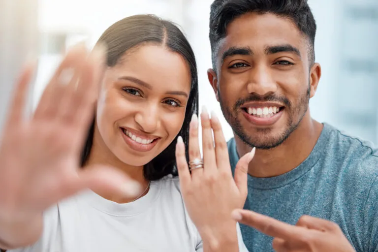 A couple posing with an engagement ring on her finger